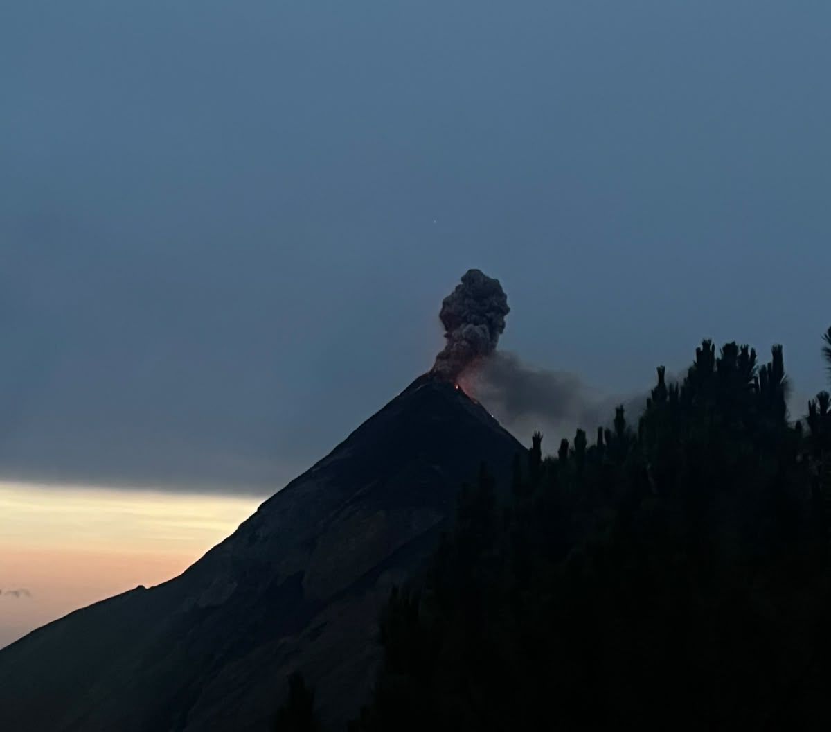 Fuego volcano releasing an ash plume at dusk, seen from Acatenango high camp