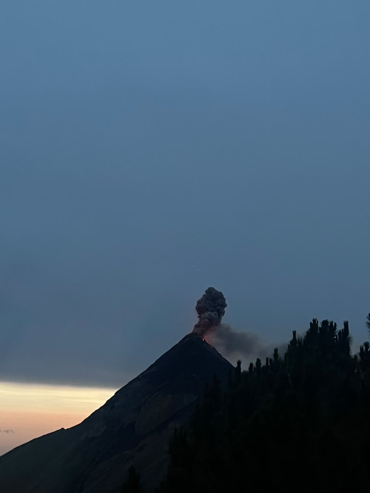 Fuego volcano releasing an ash plume at dusk, seen from Acatenango camp