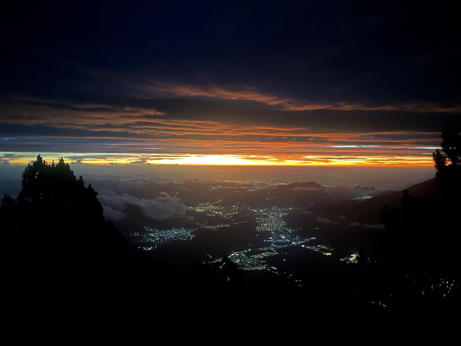 Sunrise spilling over the highland valley with town lights below Acatenango