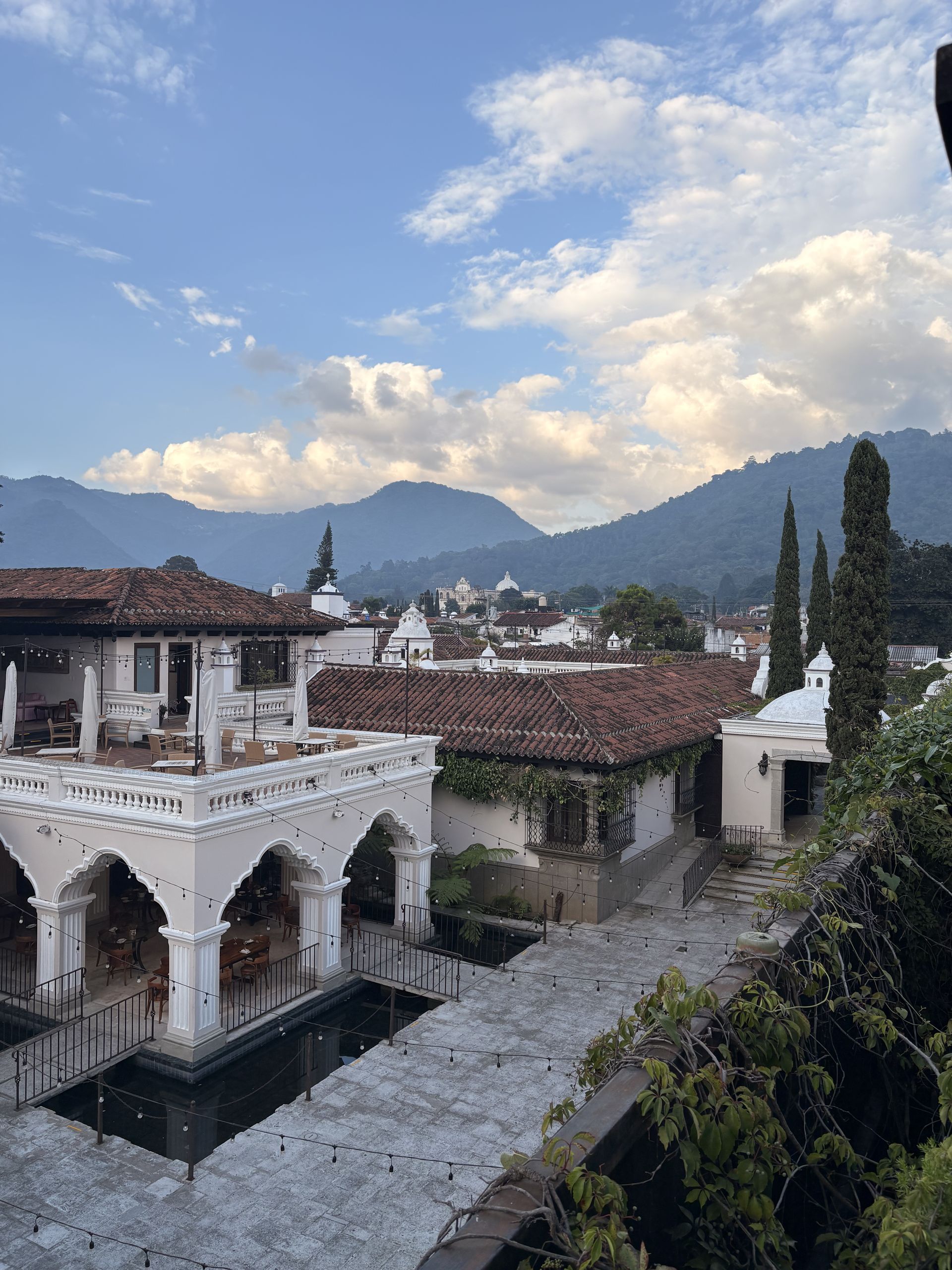 White colonial arcade and courtyard in Antigua Guatemala with volcanic hills behind
