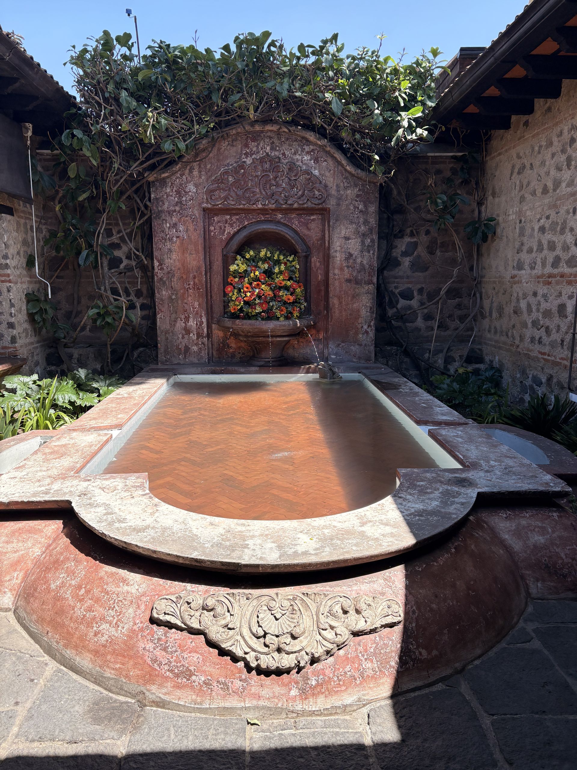 Stone courtyard fountain surrounded by greenery in Antigua Guatemala