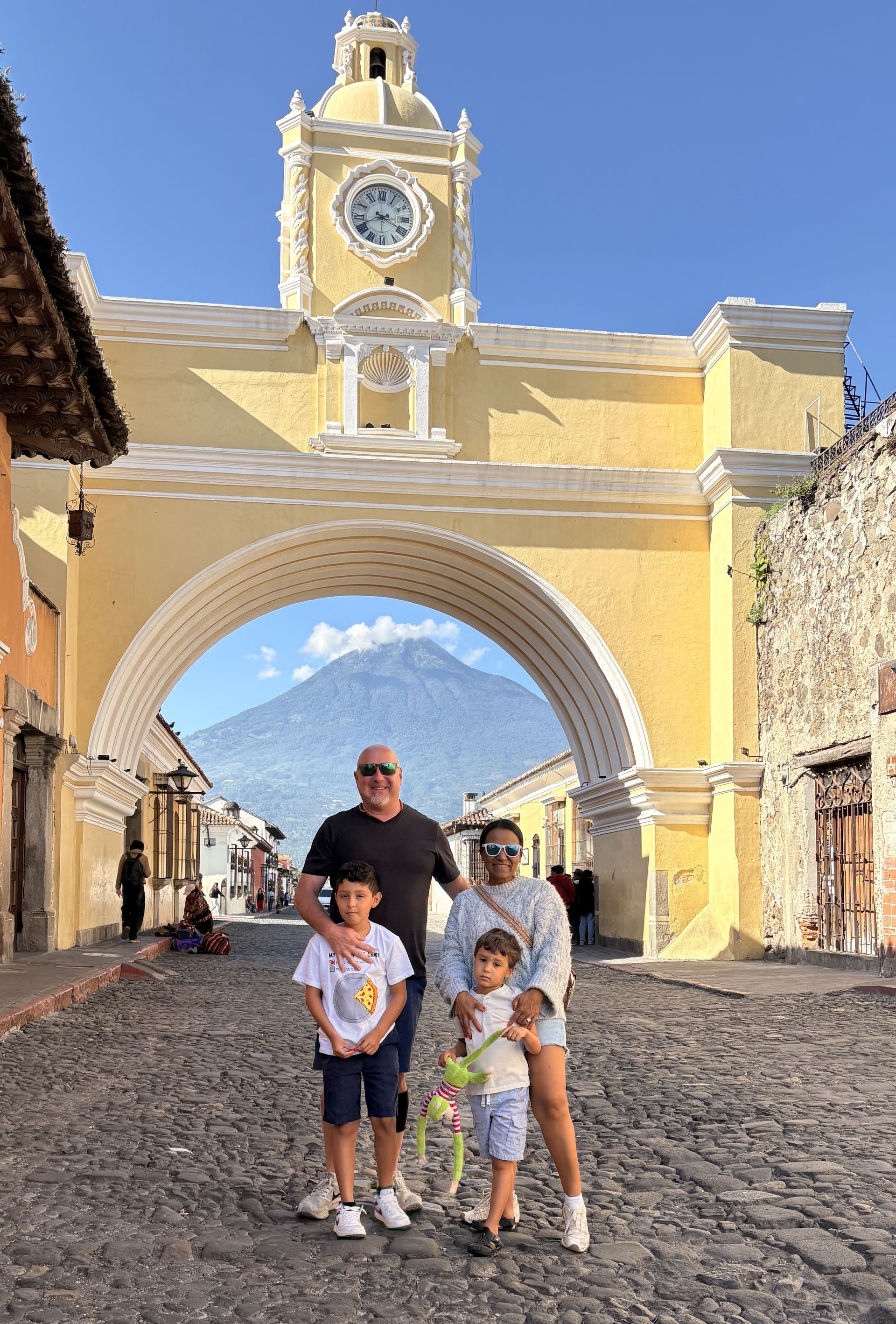 A family standing beneath the Santa Catalina Arch in Antigua Guatemala