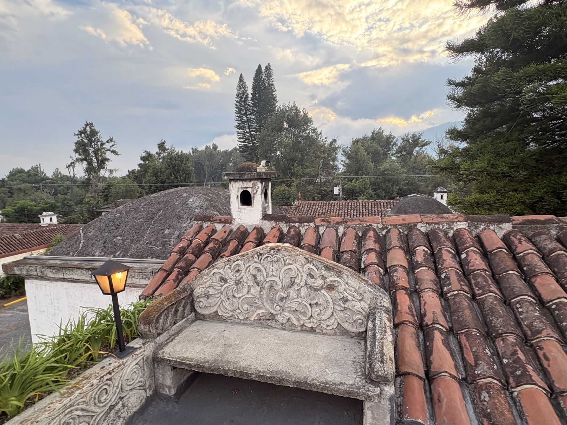 Terracotta tiled rooftops of Antigua Guatemala with Volcán de Agua rising behind afternoon cloud