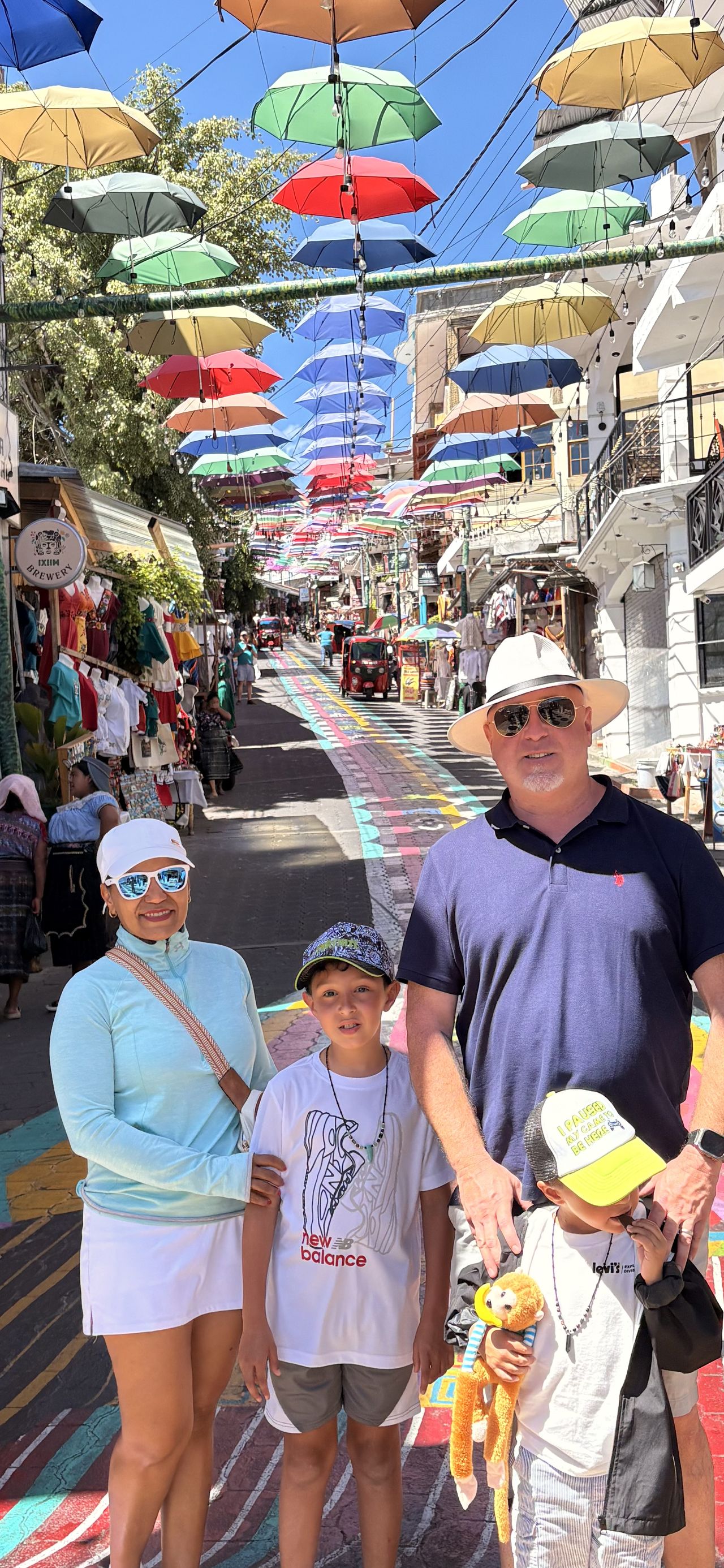 A family walking a street of hanging umbrellas in Antigua Guatemala