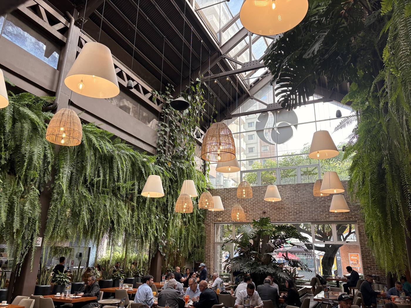 Fern-filled restaurant interior with rattan lamps and a skylight in Guatemala City