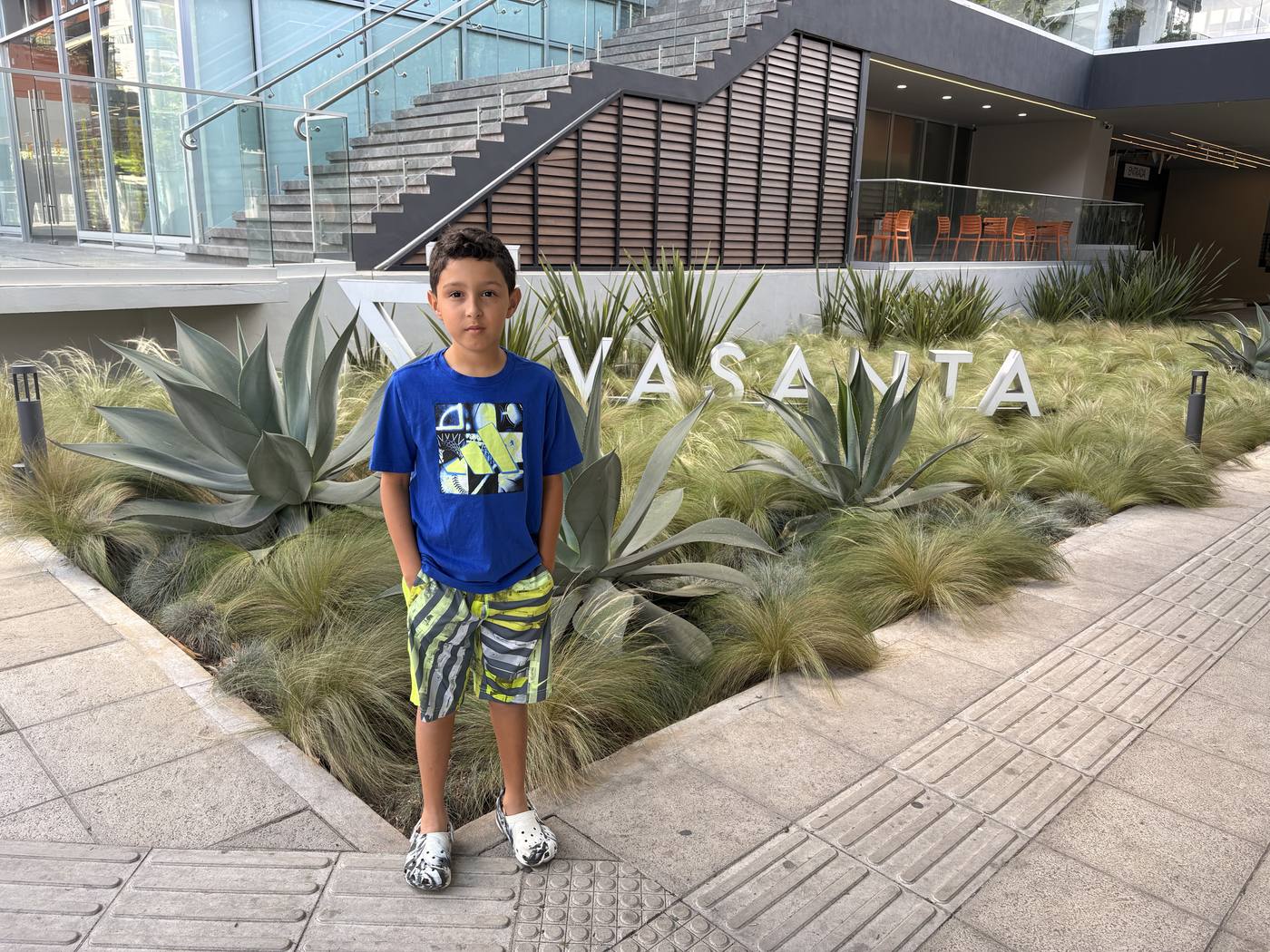 A boy standing by the Vasanta sign amid agaves on 6a Avenida, Zona 10